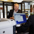 A person at a hotel reception desk talking to another person behind a computer. 