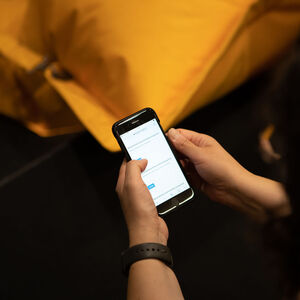 Kädet pitelevät puhelinta, jonka näytöllä lukee "kysymyksiä ja kommentteja työpajoista."