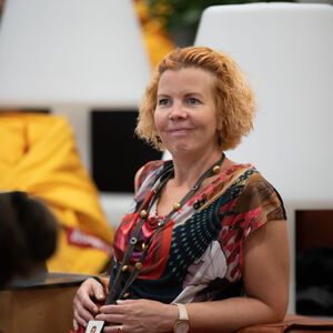 Nainen yleisössä hymyilee ja katsoo eteenpäin.