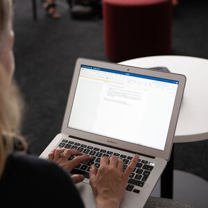 Henkilö kirjoittaa muistiinpanoja tietokoneelle.