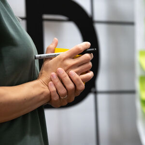 Hands are holding a pen. There are post-it-notes attached on the whiteboard.