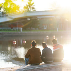 3 ystävää istuu rannalla