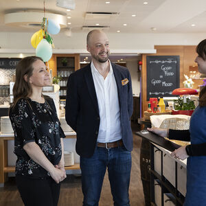 Juhlapaikan työntekijä keskustelee hääparin kanssa järjestelyistä.