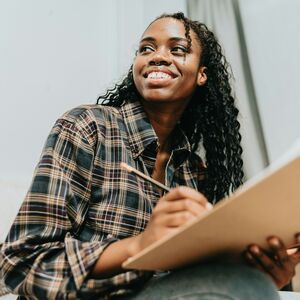 Person i en rutig skjorta som håller en mapp och en penna, kanske skriver eller ritar.