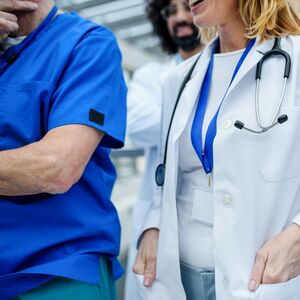 Group of medical professionals in a hospital, some in blue scrubs and one in a white coat with a stethoscope.