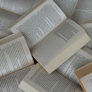 En hög med öppna böcker som överlappar varandra, med sidor fyllda av text.