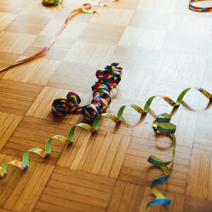 Färgglada serpentiner utspridda på ett parkettgolv.