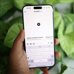 A hand holding a smartphone displaying the ChatGPT-4 app, with green plants in the blurred background.