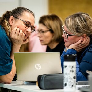 Kuvassa on opettaja ja opiskelija kannettavan tietokoneen äärellä.