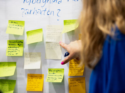 En person läser post-it-lappar som är uppsatta på väggen.