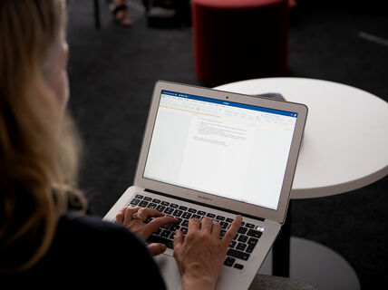 Henkilö kirjoittaa muistiinpanoja tietokoneelle.