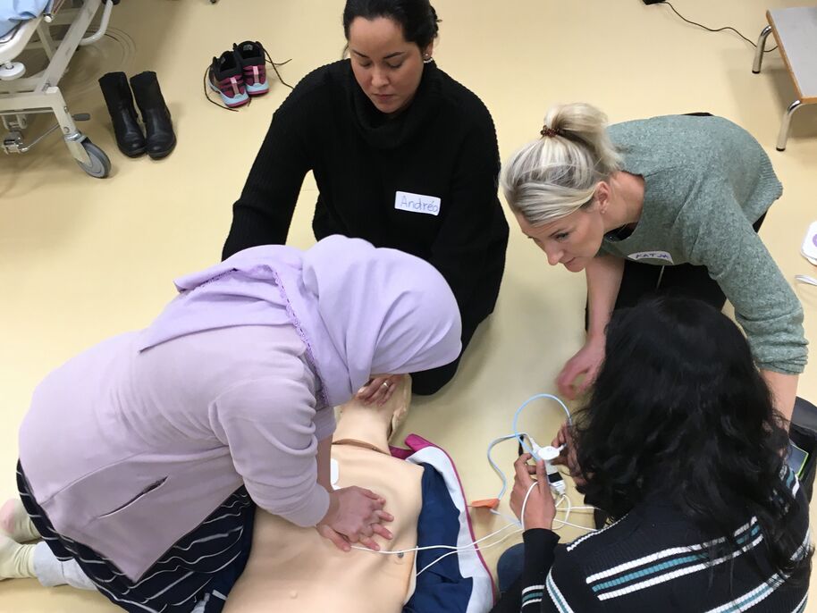 Neljä opiskelijaa harjoittelemassa elvytystä nukella.