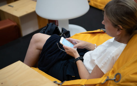 A woman is sitting in a beanbag and she is surfing on her mobile phone.
