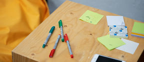There are felt-tip pens, post-it notes and a mobile phone on the table.