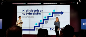 A photo of the Launch of kielibuusti.fi online portal event with an image of Steps Towards Language Awareness in the Workplace.