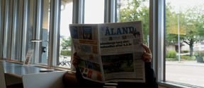 En person läser Ålands tidning på biblioteket i Mariehamn. 